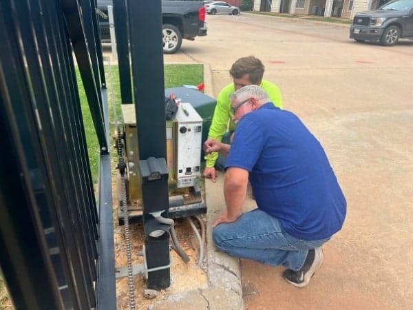 Two Fence OKC technicians repairing a gate operator in Oklahoma City, Oklahoma.