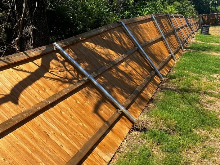 A broken wooden fence with visible Oklahoma storm damage, needing repair.