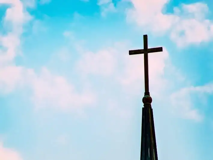 Church Steeple in OKC – Secure Fence Installation for Sacred Spaces. Church steeple with cross under blue sky in Oklahoma City, representing church fence installation.